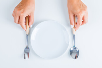 Meal concept with empty plate on white background flat lay. hands holding fork and spoon.