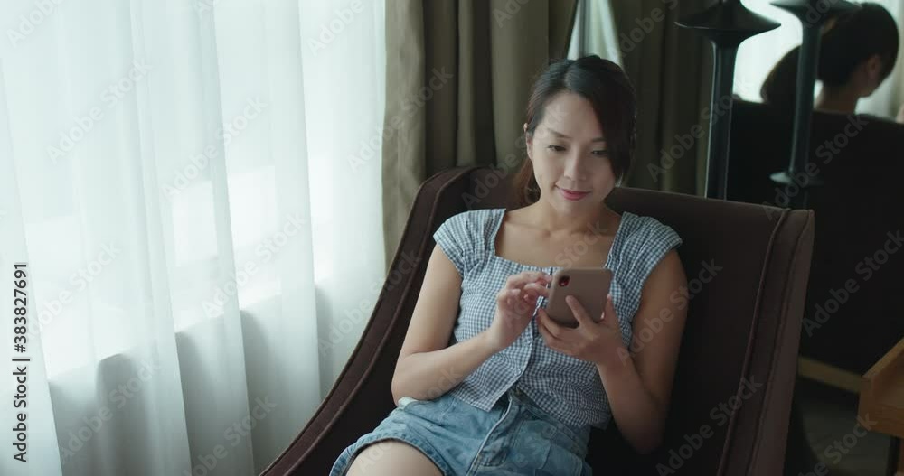 Wall mural woman use of smart phone and sit on sofa