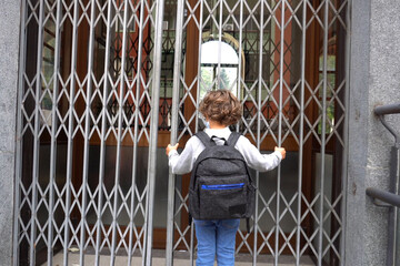 child mask and backpack goes back to school after lockdown due to Covid-19 Coronavirus global pandemic - arrives to the school closed