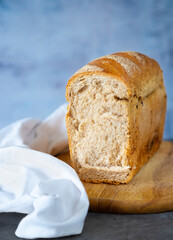 Cut homemade bread. A loaf of bread on a wooden cutting board with a light napkin 