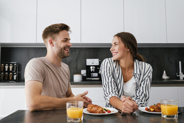 Young caucasian couple sitting at table while having breakfast at home