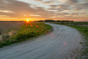 The glow of the setting sun and a turn on a gravel road
