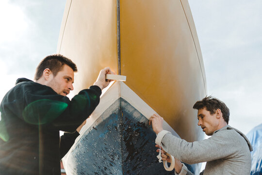Men sticking masking tape on boat