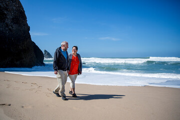 Smiling couple walking on beach - 383832635
