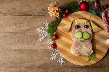 edible bull, symbol of 2021. A funny sandwich in the shape of a bull made of ham, cheese, bread, with a cucumber. children's breakfast.  New Year's, Christmas food.