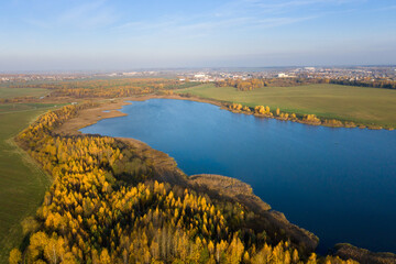 Obraz premium Autumn panorama. Aerial view on woods, lake and town. Sunny autumn day above woods and lake. Beautiful october. 