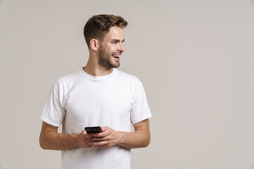 Photo of excited handsome guy smiling and using mobile phone