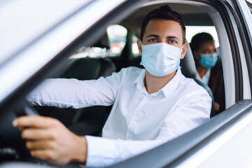 Fototapeta na wymiar Man driving a car in protective sterile medical mask during an epidemic in quarantine city. Covid- 19.