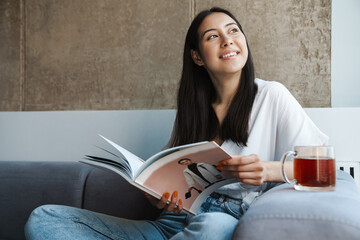 Positive optimistic young woman reading magazine