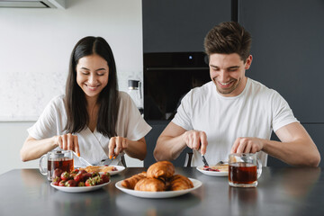 Obraz na płótnie Canvas Positive young loving couple at home having a breakfast