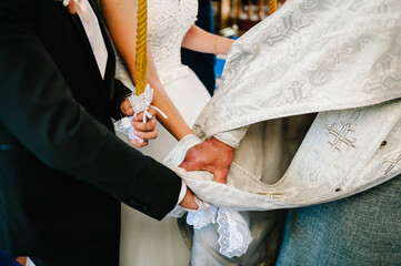 Hands of bride and groom tied Wedding towel. The priest binds the bride's hand towel. hands of young couples in the church. Wedding day.
