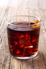 Boulevardier cocktail and orange zest on wooden table. 	