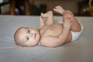 A little four-month-old girl is lying on the sofa in the room.