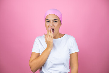 Young beautiful woman wearing pink headscarf over isolated pink background bored yawning tired covering mouth with hand. Restless and sleepiness.