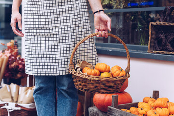 Woman holding a basket with pumpkins in her store.