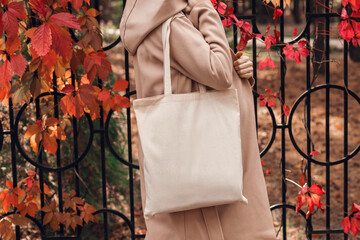 Woman in coat with white cotton bag in her hands. Mockup and zero waste concept.
