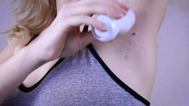 Woman applying deodorant exercising fitness workout. Bad smell of sweat, excessive sweating, hyperhidrosis.