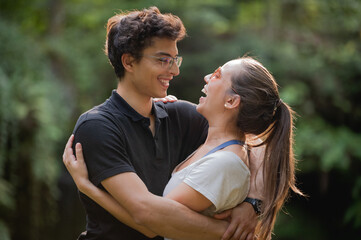 Young couple tenderly looks at each other, hugging and laughing.