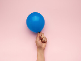 female hand holding an inflated blue air balloon