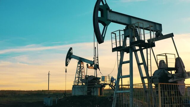 Metal units are pumping oil at the development site. Oil well, crude oil, drilling rig, oil field, crude oil price, oil and gas, oil barrel, oil industry concept.