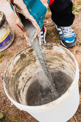 Builder pours cement into a bucket to mix mortar - bricklayer job - dry mortar