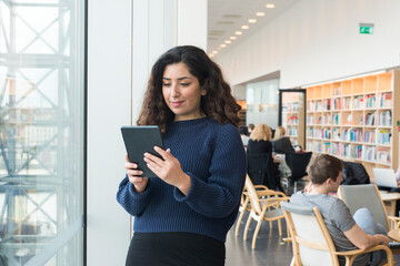 Woman using digital tablet in library