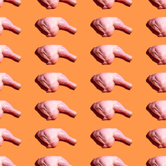 Seamless pattern with raw chicken leg on orange background.