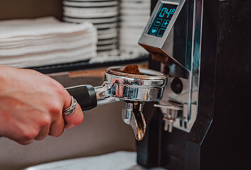 barista hand grinding fresh coffee into bayonet by the coffee grinder