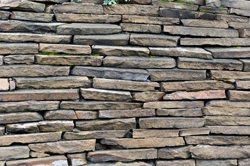 Flat stone sides laid in several rows horizontally. Old stone wall.