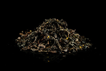 pile of dry green tea on a black background