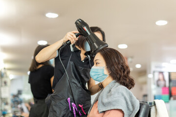 Woman at hairdresser wearing protective mask due to coronavirus pandemic.