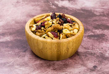 Wood bowl filled with healthy trail mix on a tabletop.