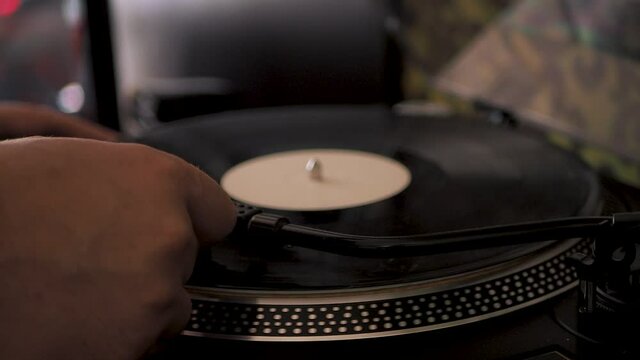 Close-up male hand starting record player, put  the needle on record, selective focus. Gramophone and record to listen to. Included turntable, arm and torque plate close-up on a light background.Sc C