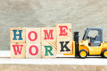 Toy forklift hold letter block e and k to complete word homework on wood background © bankrx