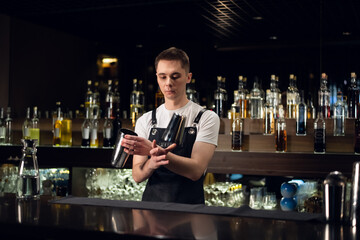 a young bartender hosts a show with shakers at the bar in a nightclub.