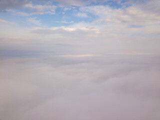 Aerial drone flight over the fog. There are thick clouds of fog below, cloudy.