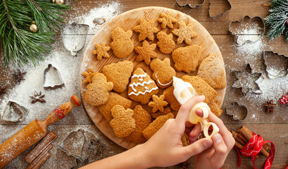 The process of cooking gingerbread. The boy decorates ginger biscuits with white icing sugar.