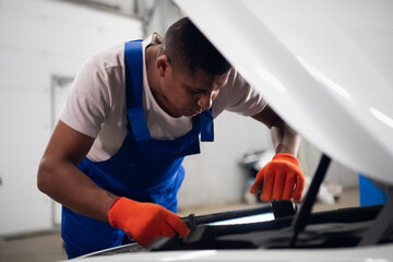 Uniform machinist uses a flashlight to inspect a car engine