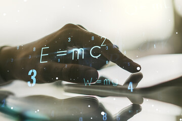 Creative scientific formula hologram and hand working with a digital tablet on background, research concept. Multiexposure