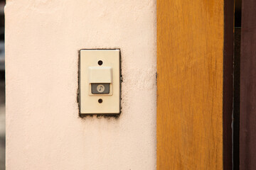 close up and front view of bell or buzzer is on the plaster wall in entry front of the house for security and safety to the resident. The copy space with blurred background is shown