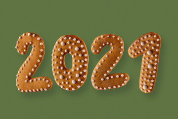 Gingerbread cookie in the form of the numbers 2021 on a green neutral background. New year concept