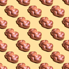 Seamless pattern with challah bread for Shabbat on yellow background.