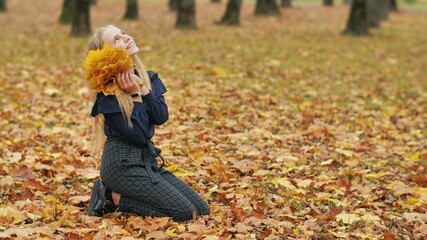 Teenager girl collects autumn leaves in the park and posing.