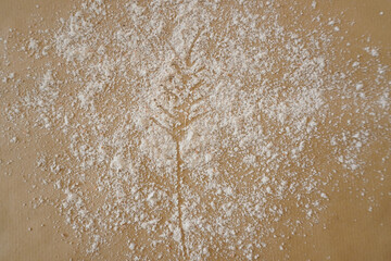 A wheat spike drawn in flour with a rustic background