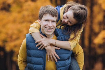 Fototapeta premium Portrait of a happy couple in autumn park, guy looking at camera and smiling