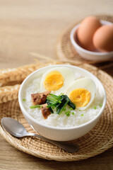 Asian food, Rice soup with boiled egg, grilled mushroom and spinach in a bowl on woven rattan sheet