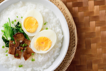 Asian food, Rice soup with boiled egg, grilled mushroom and spinach in bowl on woven bamboo sheets