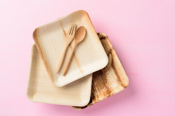 Betel palm leaf plate (Biodegradable plate, Compostable plate or Eco friendly disposable plate) with wooden fork and spoon on pink background