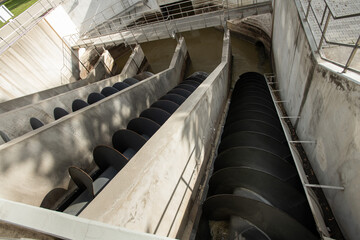 schmutziges Abwasser wird über Schneckenspiralen im Klärwerk zur ersten Reinigungsstufe transportiert.