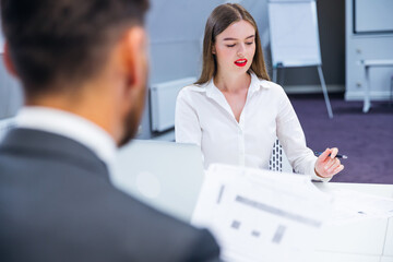 Fototapeta premium Attractive businesswoman, teacher or mentor trainer talking with young people, girl teaching audience at training seminar, woman business leader speaker at meeting.